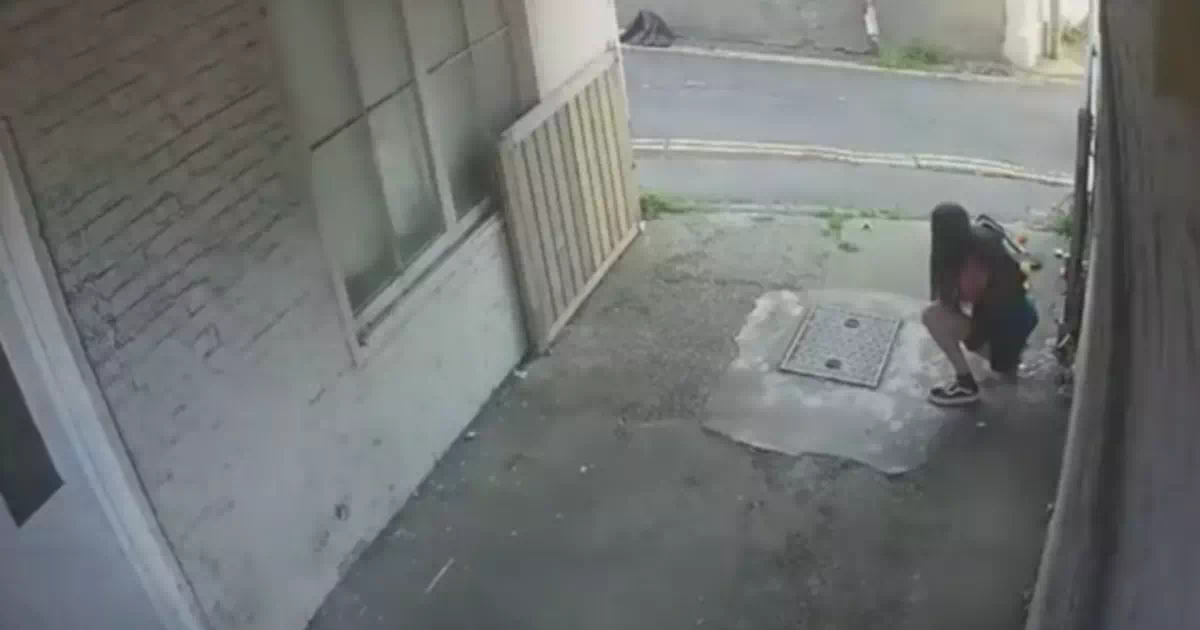 他人の家の駐車場で堂々と野ションする女性。付き添いの男は見ないようにする。